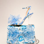 blue and white floral print hand bag with oversized bow that has pearl like detail with shoe