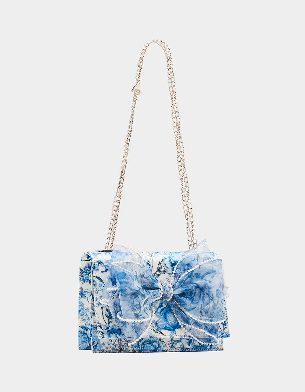 blue and white floral print hand bag with oversized bow that has pearl like detail with strap detail
