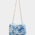 blue and white floral print hand bag with oversized bow that has pearl like detail with strap detail