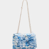 blue and white floral print hand bag with oversized bow that has pearl like detail with strap detail