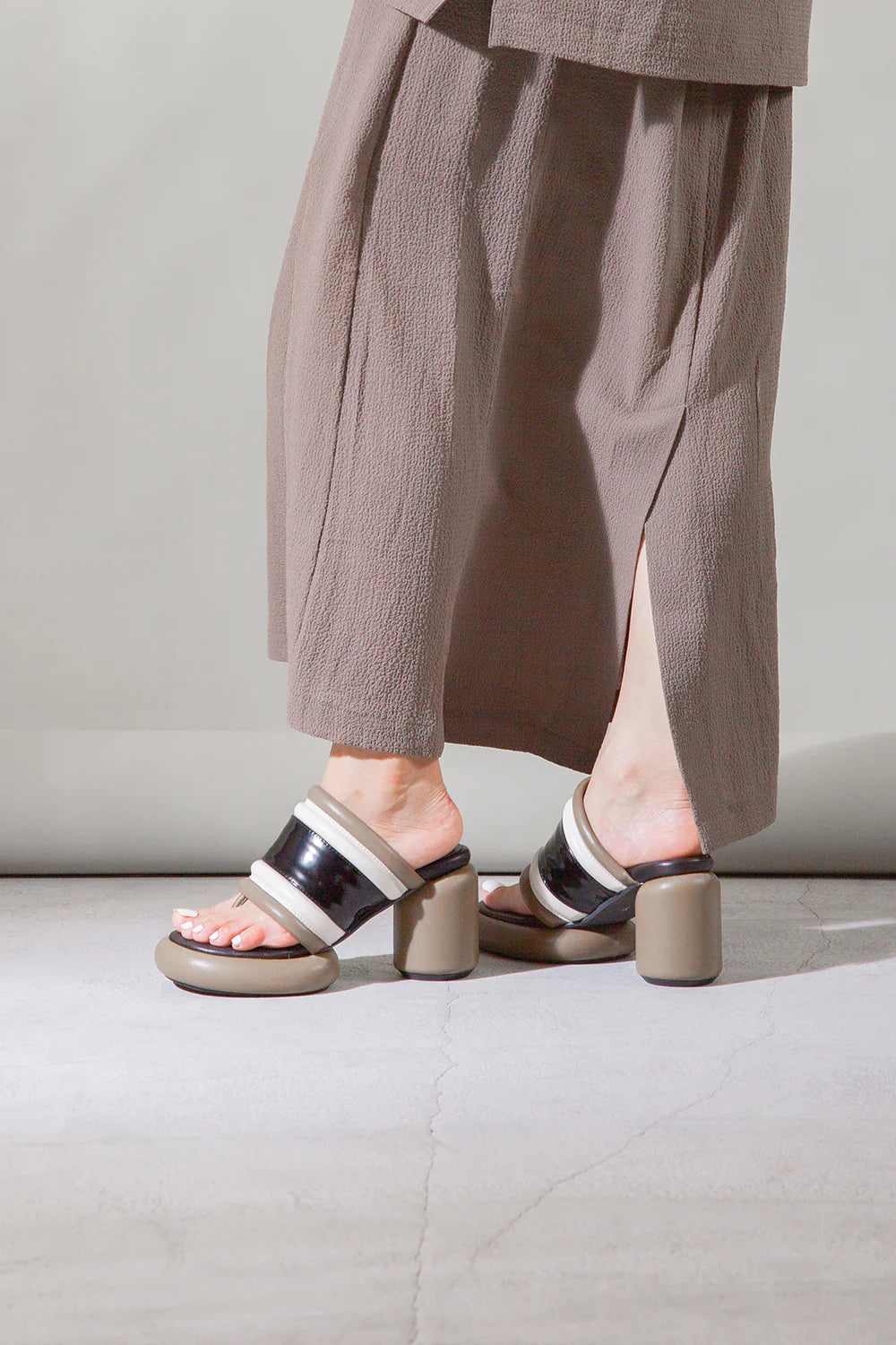 Brown, black, and white bubble modern backless heel sandal pair on model
