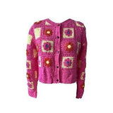 Pink crocheted cardigan with a pattern of colorful squares and flowers on a white background