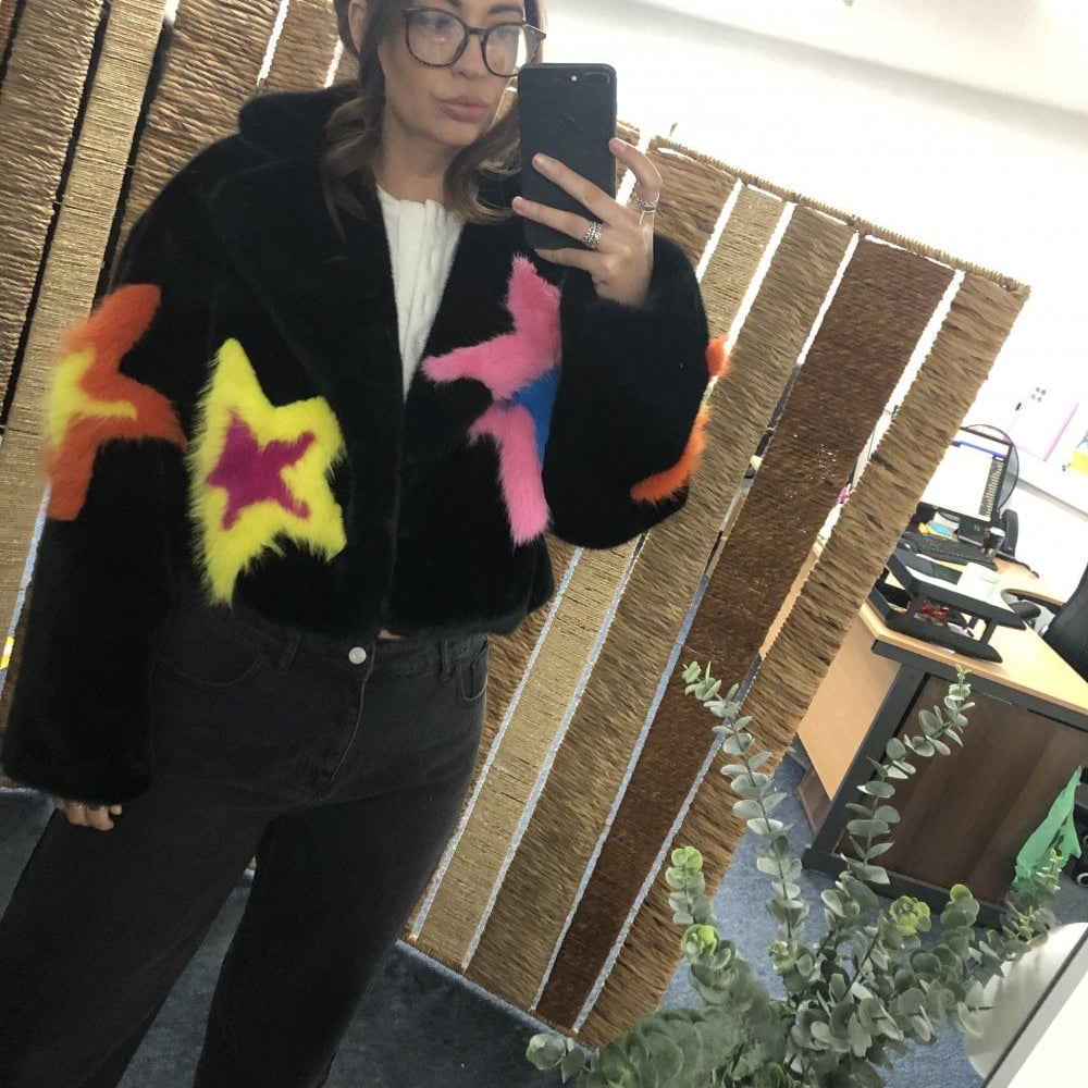 Black fur like jacket with colorful star designs on a model