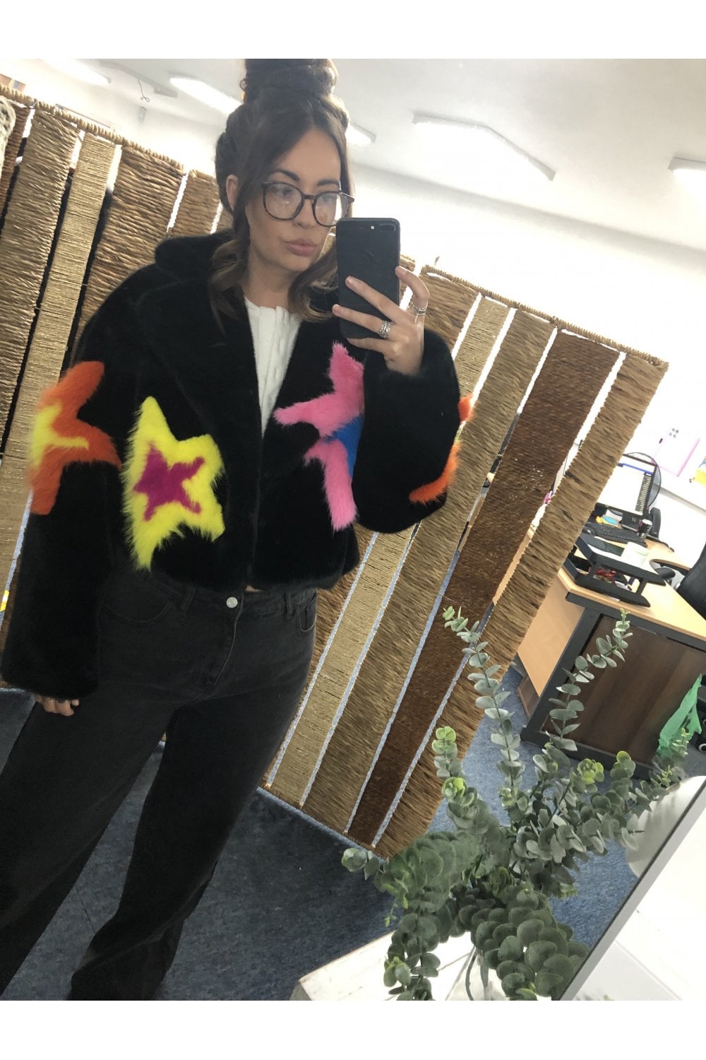 Black fur like jacket with colorful star designs on a model