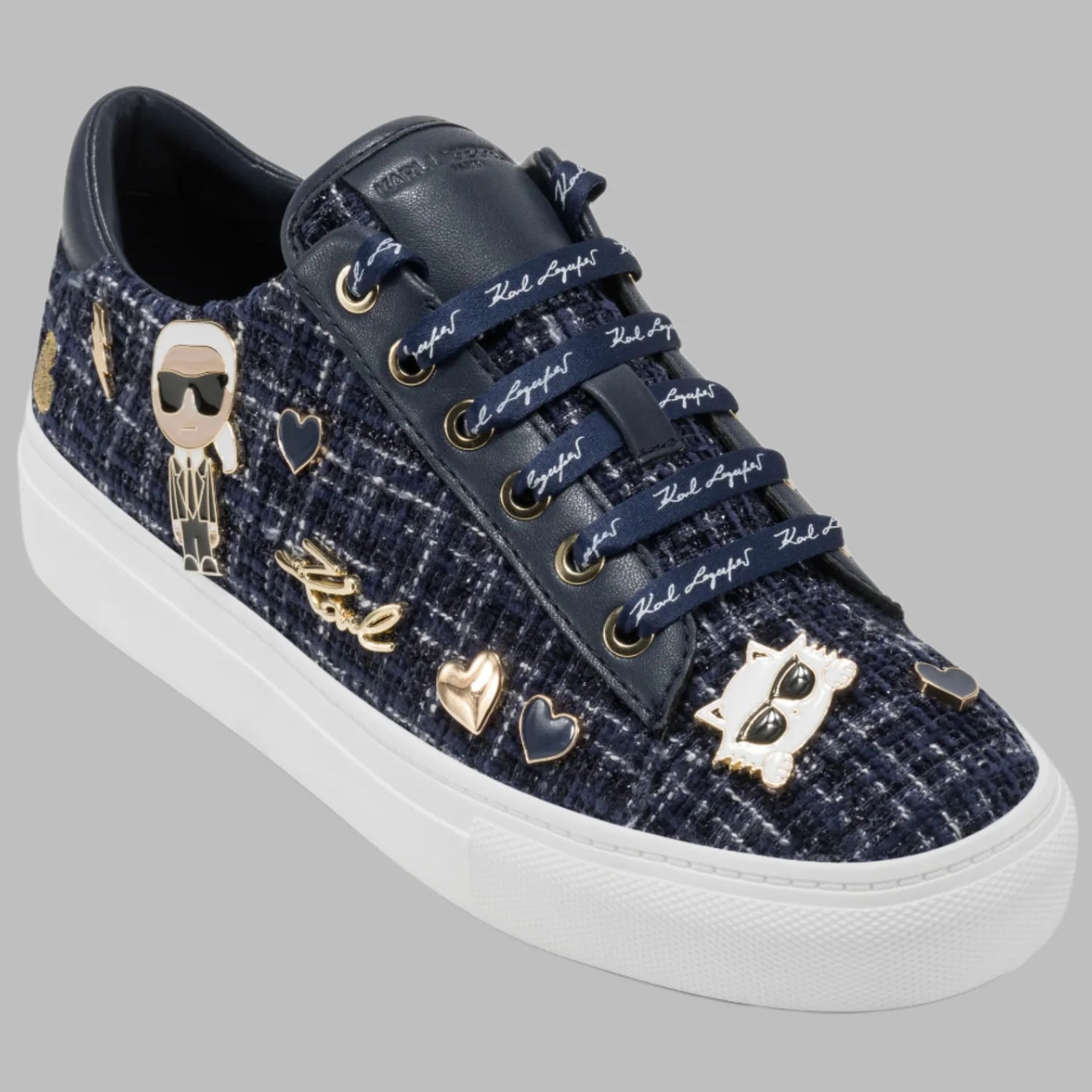 Black sneaker with decorative hearts and cat pins on a gray background