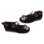 Black furry mary janes with cartoon lamb faces and decorative bow, bell, and pentagram elements on a white background side by side