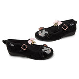 Black furry mary janes with cartoon lamb faces and decorative bow, bell, and pentagram elements on a white background side by side