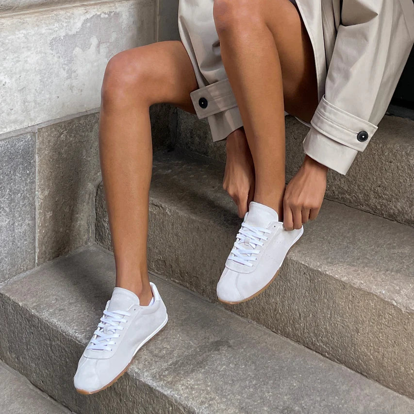 Italian-made sneaker featuring a trendy silhouette in ultra-soft suede. The SERINA sneaker in ivory features a rubber sole and white shoe laces on model.