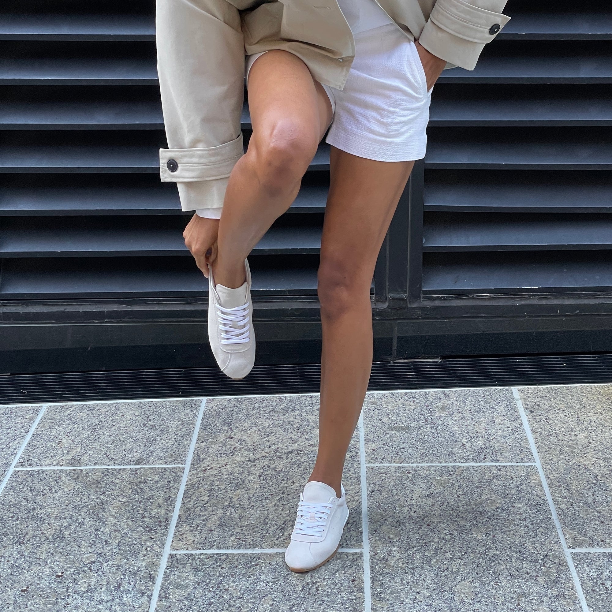 Italian-made sneaker featuring a trendy silhouette in ultra-soft suede. The SERINA sneaker in ivory features a rubber sole and white shoe laces pair on model.