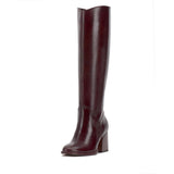 Brown knee-high tall shaft boot with soft round toe and a stacked block heel. Has zippered side closure and elastic inserts on the shaft for improved fit. The boot is lined with fabric and finished on the exterior with a leather-covered welt and rubber outsole side front