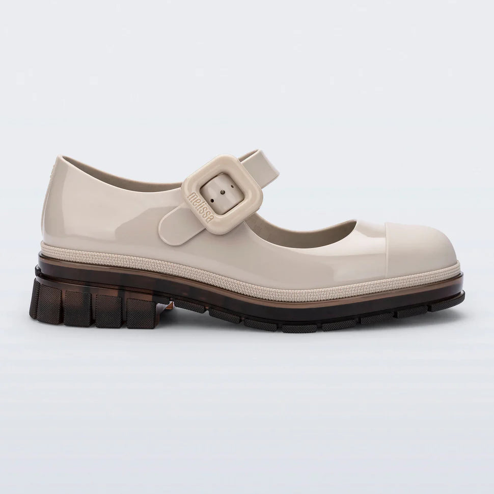 The June  Mary Jane by Melissa features a neutral beige hue, slight heel, fun bubblegum scent, and large buckle detail side profile
