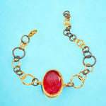 Bracelet with a red stone center on a gold and silver large loop chain on a blue background