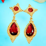 Gold earrings with red gemstones on a light blue background