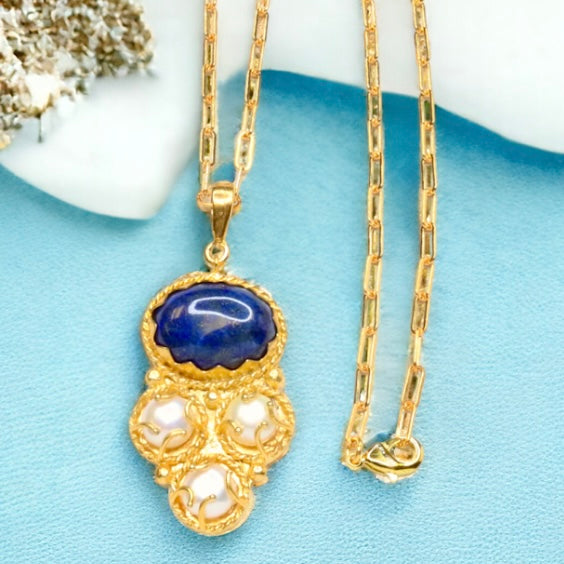 Gold colored necklace with a blue pendant and pearl-like elements with elongated link chain