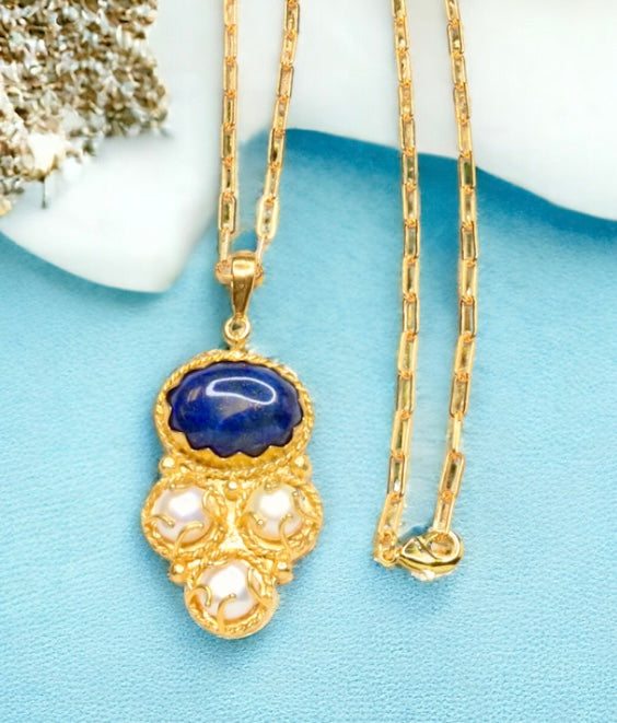 Gold colored necklace with a blue pendant and pearl-like elements with elongated link chain