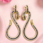 Gold snake-shaped earrings with blue and red crystals on a pink background