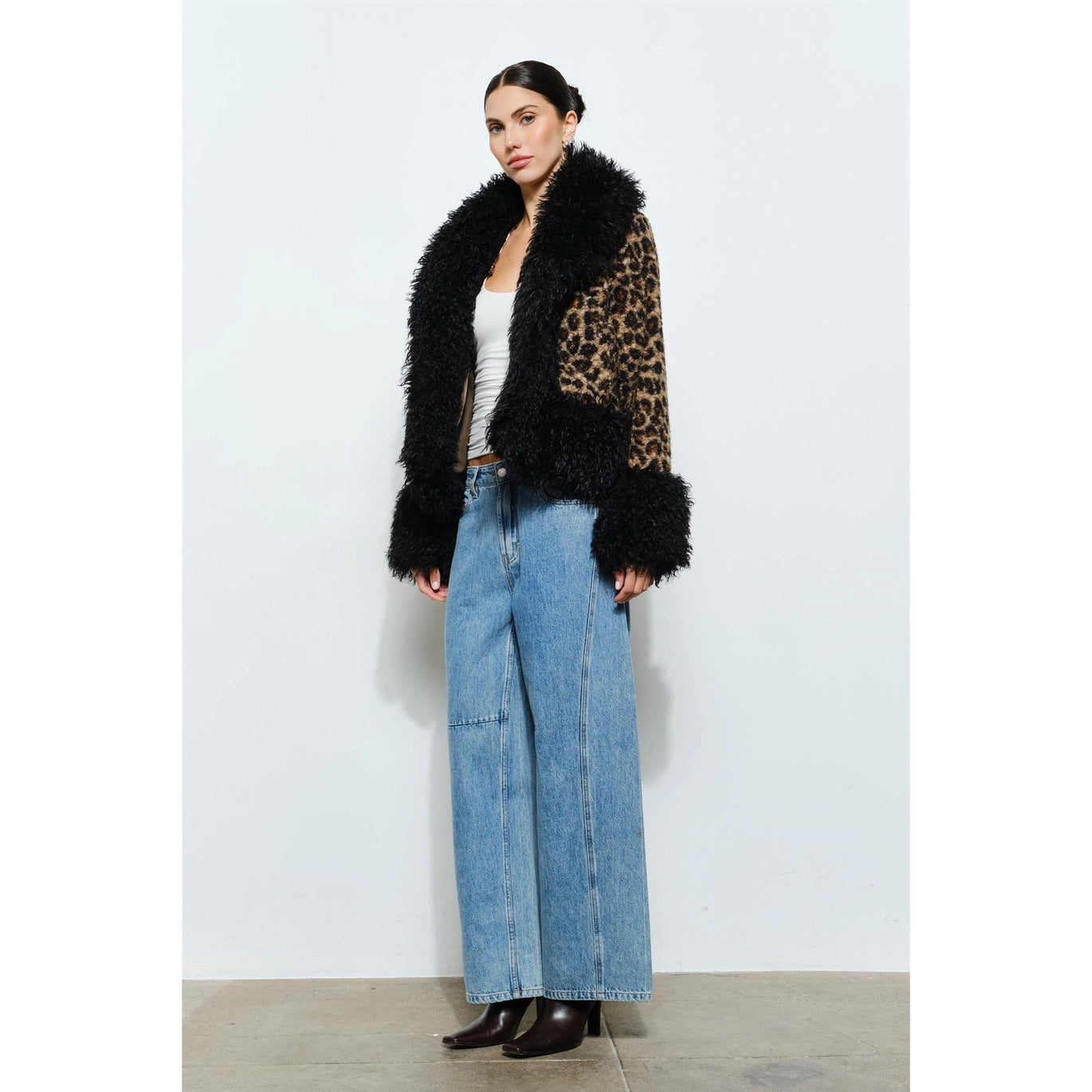 Woman wearing a leopard print coat with black faux fur trim on a white background showing full body to show length of jacket