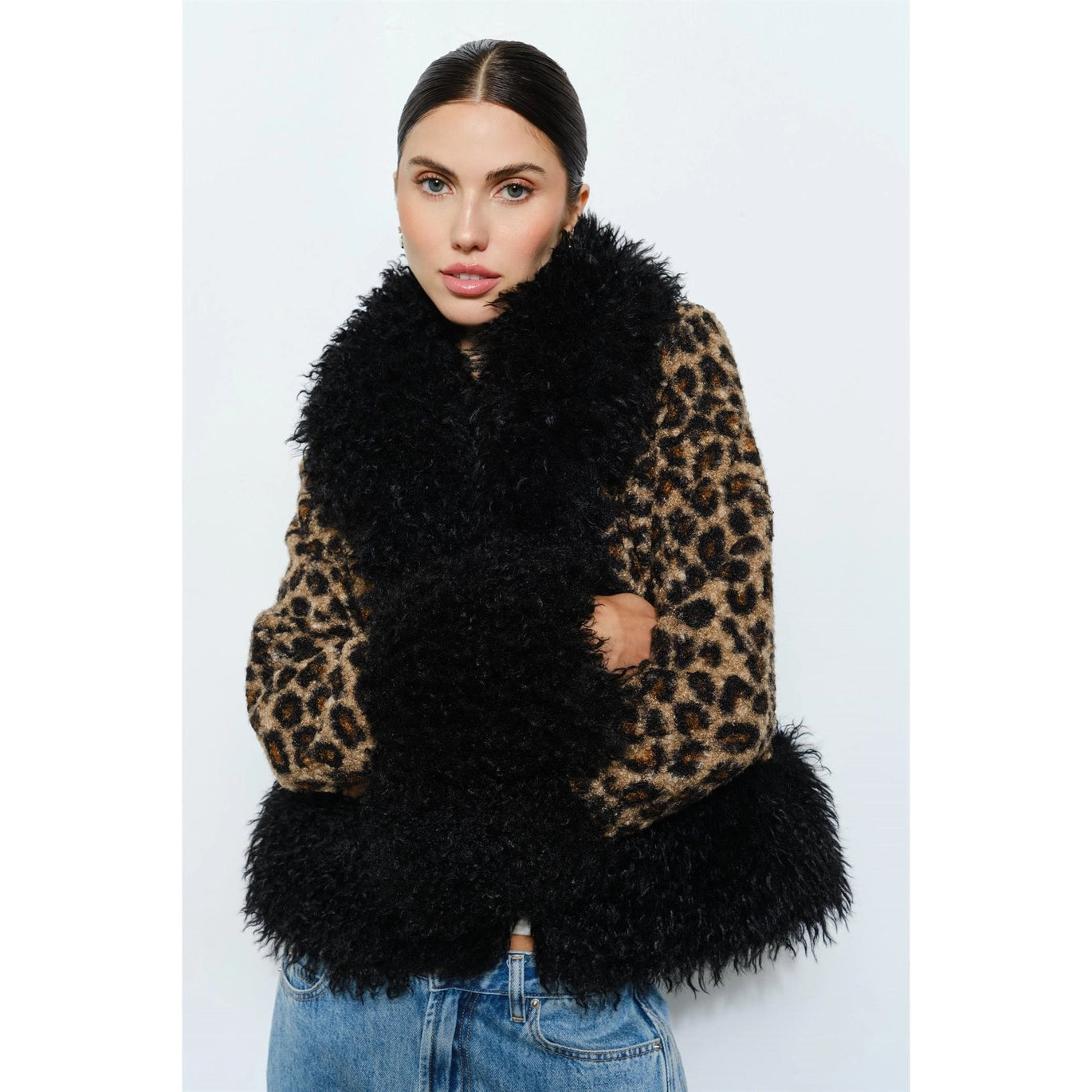 Woman wearing a leopard print coat with black faux fur trim on a white background
