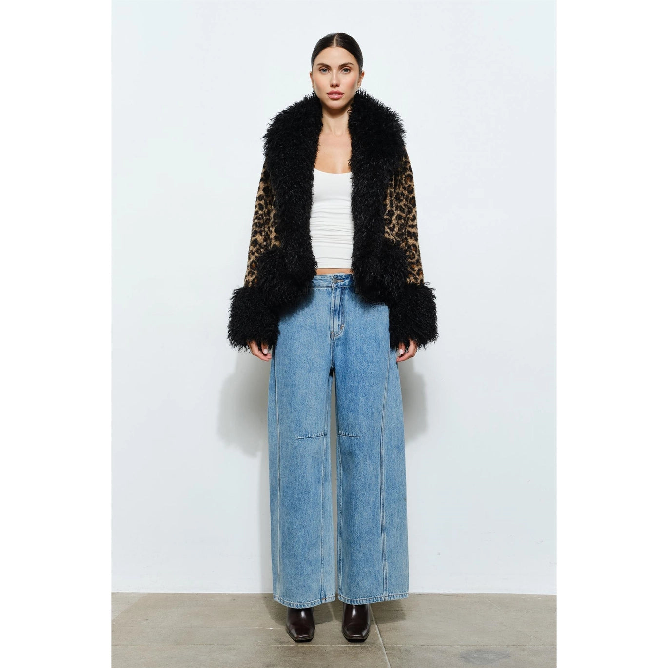 Woman wearing a leopard print coat with black faux fur trim on a white background showing front of coat