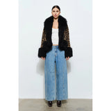 Woman wearing a leopard print coat with black faux fur trim on a white background showing front of coat