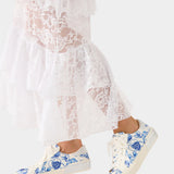 White lace dress with blue floral sneakers on a white background