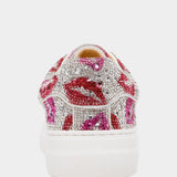 White sneaker with pink and red lip designs and rhinestones on a white background