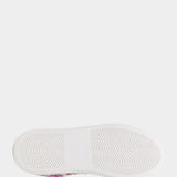 Close-up of a white sneaker sole with a patterned shoe visible at the edge on a light gray background.