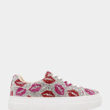 Sneaker with lip print embellishments on a white background