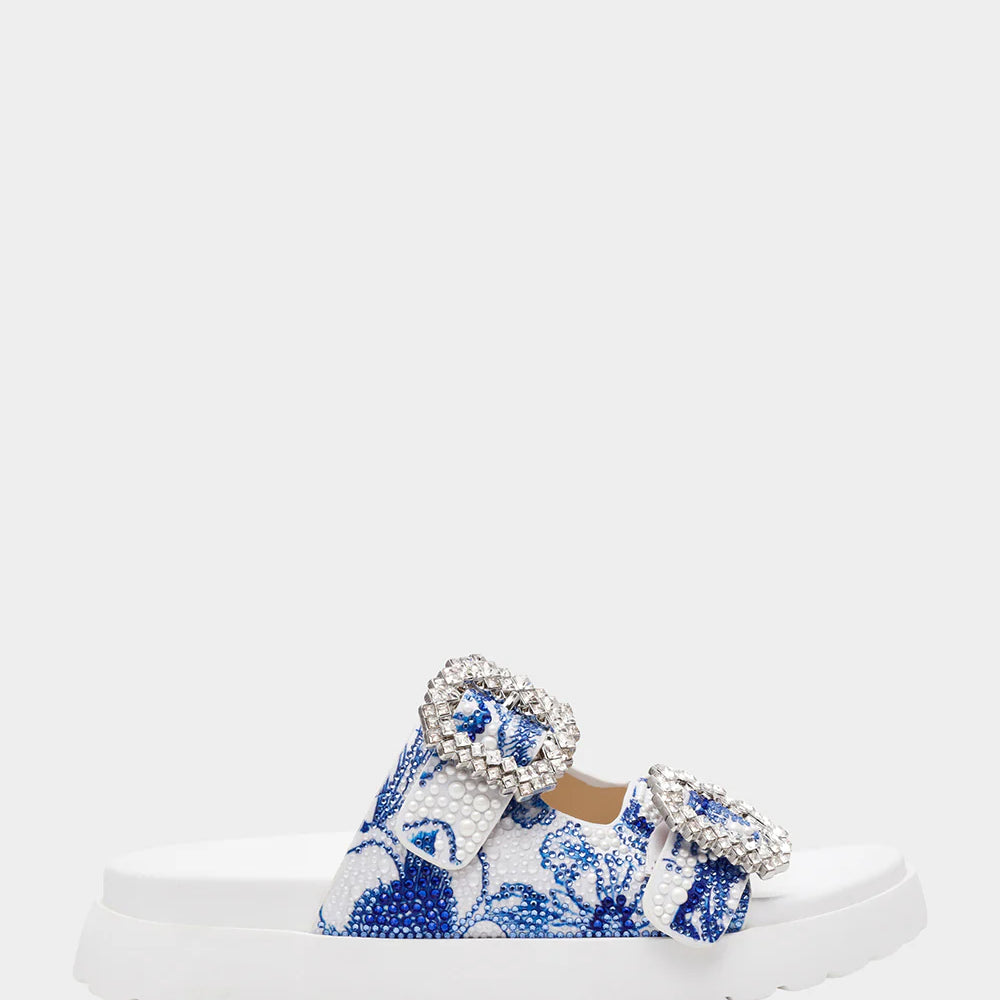 White sandal with blue bejeweled floral pattern and embellishments close-up