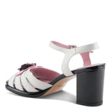 Open toe heeled shoe with white strap, black sole, and pink flower inner side view