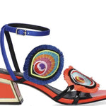 Colorful heel with peacock feather elements and blue strap buckle closure close-up