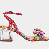 Colorful sandal with floral design, ankle strap, floral applique, and a clear heel close up