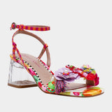 Colorful sandal with floral design, ankle strap, floral applique, and a clear heel from side