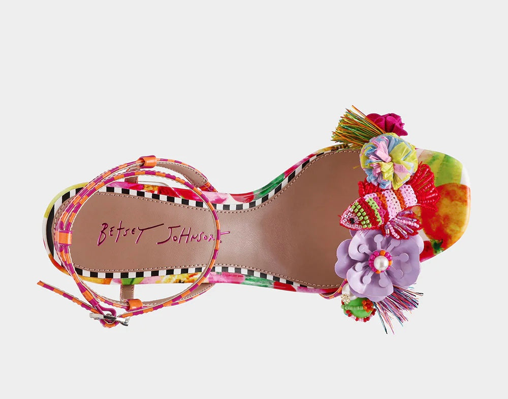 Colorful sandal with floral design, ankle strap, floral applique, and a clear heel birds eye view