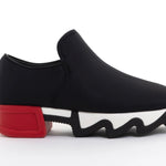 Black slip-on shoe with a red heel and black & white sole close-up
