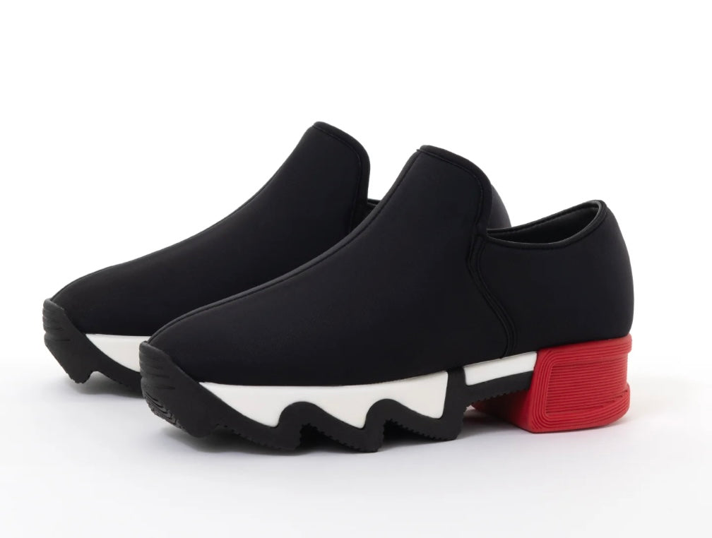 Black slip-on shoe with a red heel and black & white sole pair
