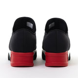 Black slip-on shoe with a red heel and black & white sole heel view