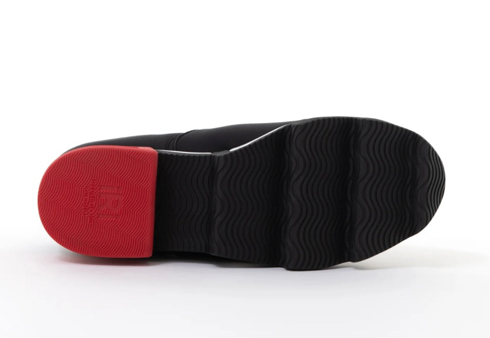 Black slip-on shoe with a red heel and black & white sole sole view