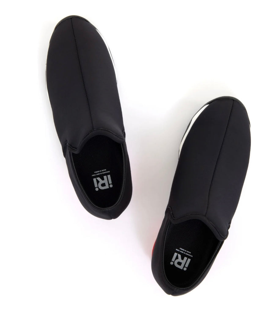 Black slip-on shoe with a red heel and black & white sole top view