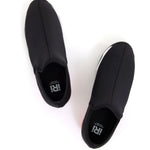 Black slip-on shoe with a red heel and black & white sole top view
