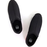 Black slip-on shoe with a red heel and black & white sole top view