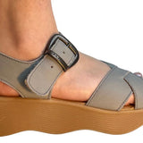 Gray sandal with a brown platform sole and brass buckle closure close-up