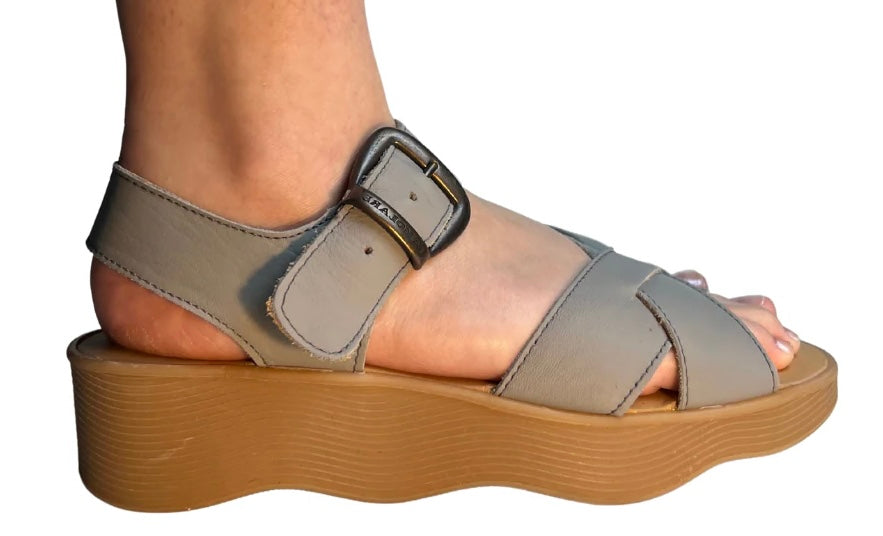 Gray sandal with a brown platform sole and brass buckle closure close-up