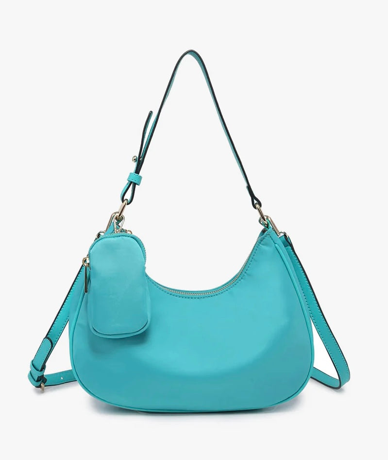 Turquoise handbag with a shoulder strap and hand strap and small accessory bag close-up