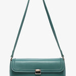 Green handbag with a strap and brass clasp close-up