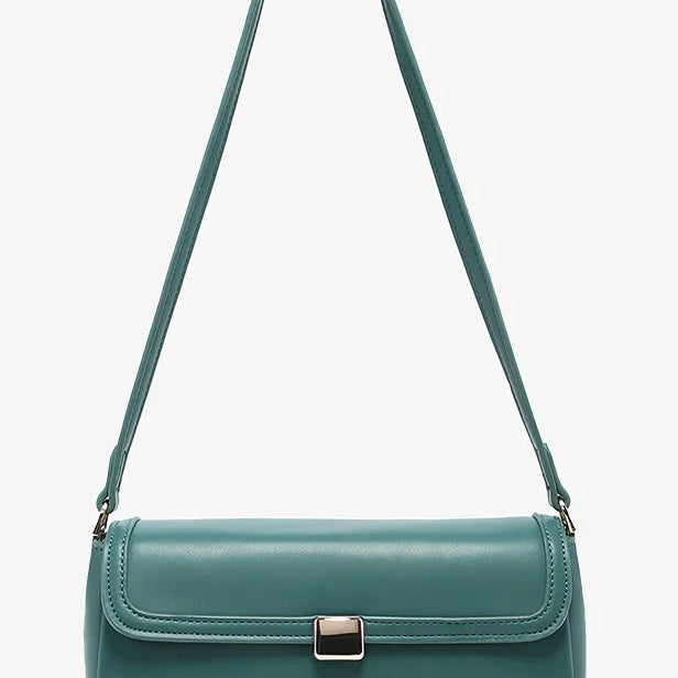 Green handbag with a strap and brass clasp close-up