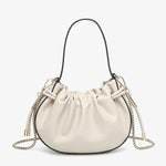 Cream handbag with chain detail and hand strap close-up