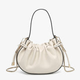 Cream handbag with chain detail and hand strap close-up