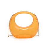 Transparent orange circular acrylic handbag with a gold chain strap close-up