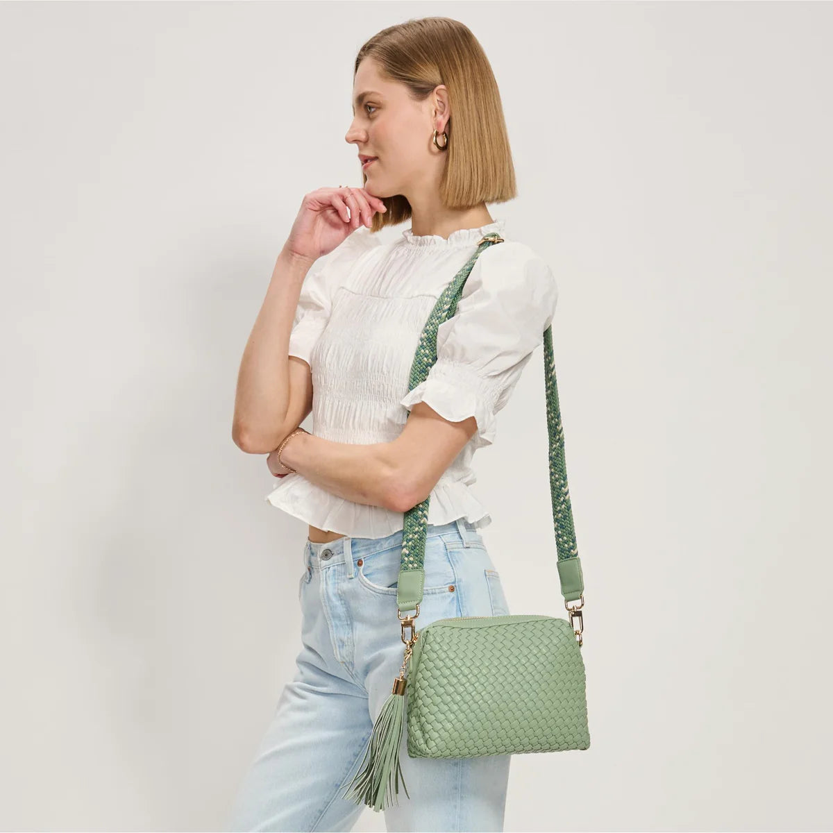 Green textured handbag with a green black and white striped strap model 